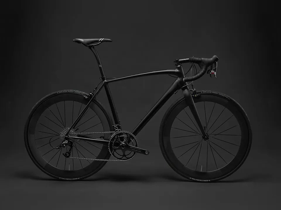 Matte black carbon road bike in side view against a dark grey studio backdrop