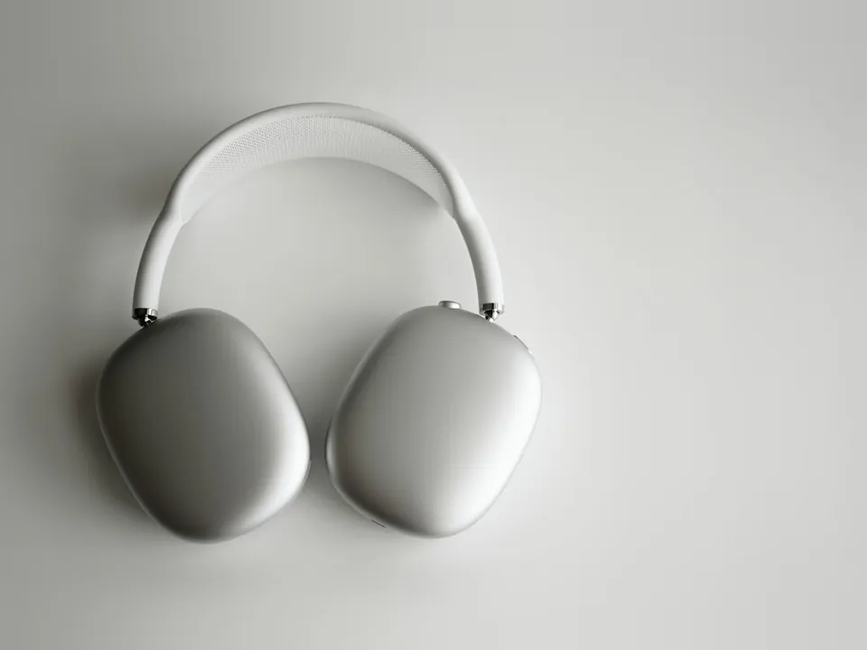 Silver over-ear wireless headphones lying on a white surface